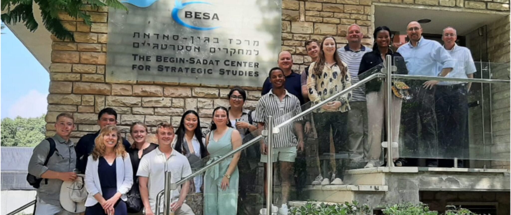 A group of people stand outside the Begin-Sadat Center for Strategic Studies, with the center's name visible on a stone building.
